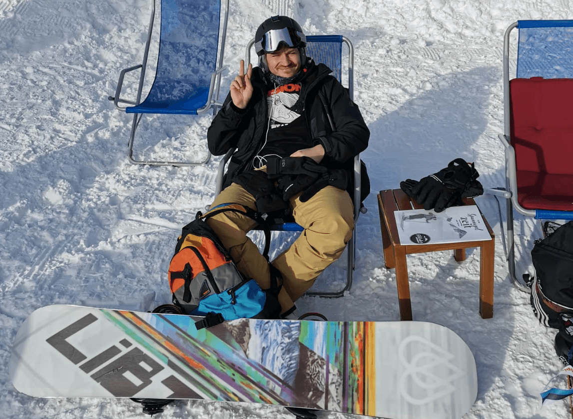 Viljar resting in the snow with a snowboard